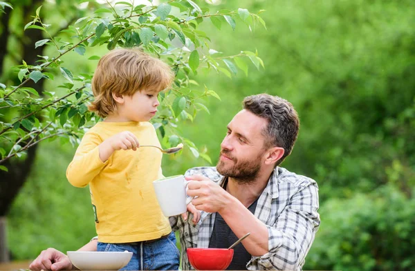 Menu for children. Family enjoy homemade meal. Food habits. Little boy with dad eating food picnic yard nature background. Summer breakfast. Healthy food concept. Father son eat food and have fun — Stock Photo, Image