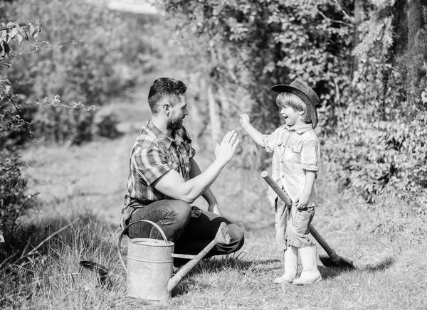 Bambino piccolo aiutare il padre in agricoltura. utilizzare annaffiatoio e pentola. Attrezzature da giardino. Azienda agricola ecologica. padre figlio in cappello da cowboy al ranch. Buon Giorno della Terra. Allevamento alberi genealogici. Metti tutto sotto controllo. — Foto Stock