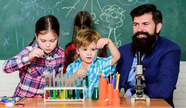 Little kids learning chemistry in school laboratory. school kids scientist studying science. happy children teacher. back to school. students doing science experiments with microscope in lab