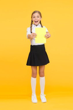 Liseli kız ders kitabı okuyor. Heyecan verici edebiyat. Kız çocuk kitapları sarı arka planda duruyor. Çocuk okul üniforması mutlu yüz okuma kitabı çalışma. Bilgi için heyecanlandım. İyi çalışmalar.