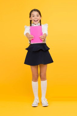 Ders kitabı okuyan liseli kız. Çocuk kız okul üniforması mutlu yüz kitap okuma. Bilgi konusunda heyecanlı. Çalışmanın tadını çıkarın. Heyecan verici bir edebiyat. Kız çocuk tutun kitap standı sarı arka plan