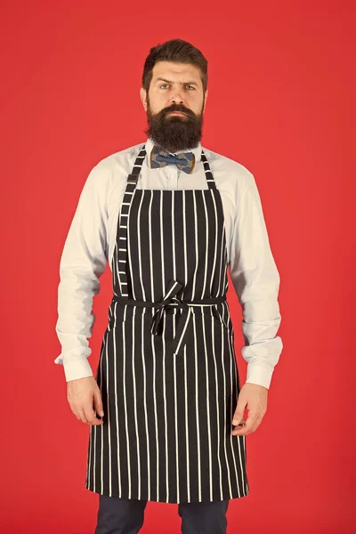 Hipster garson. Hipster kafe konsepti. Sakallı aşçı hipster önlüklü adam. Hipster şef kırmızı arka plan pişirin. Sakallı şef yemek yapıyor. Restoran personeli ve servis. Bakımlı garson iş yerinde — Stok fotoğraf