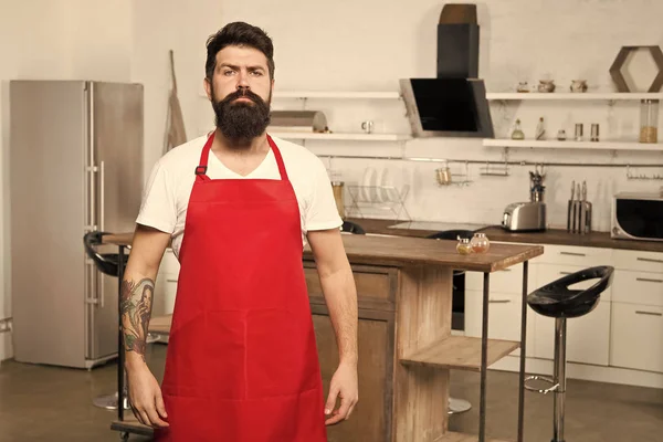 Ready to work. Man chef cooking. Mature male. Bearded man cook. Restaurant or cafe cook. Hipster in kitchen. Bearded man in red apron. Male chef in white uniform. Professional chef in kitchen