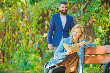 Adam kız arkadaşına randevuya geldi. Kız erkek arkadaşı beklerken bankta kitap okumak oturup. Romantik ilişkiler kavramı. Romantik bir randevu. Aşk çift romantik tarih doğa parkı arka plan. Onun için sürpriz