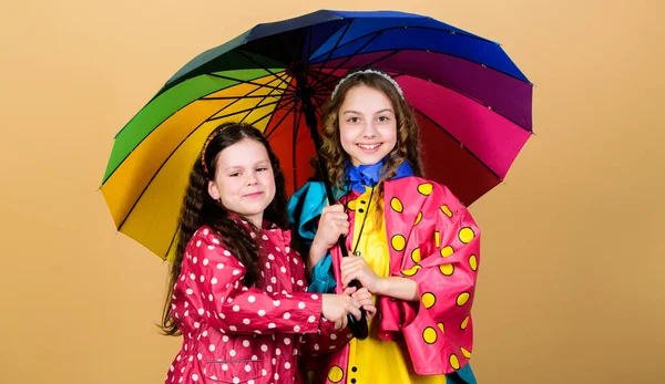 Rainy weather with proper garments. Bright umbrella. It is easier to be happy together. Be rainbow in someones cloud. Rainy day fun. Happy walk under umbrella. Kids girls happy friends under umbrella