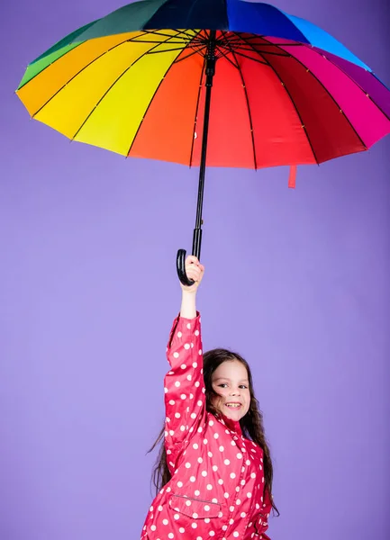 little girl in raincoat. autumn fashion. cheerful hipster child in positive mood. rain protection. Rainbow. happy little girl with colorful umbrella. Moments of joy. Free your mind
