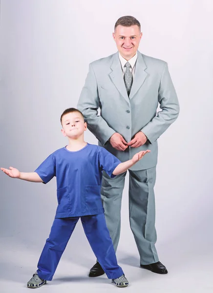Dad boss. Father and cute small son. Child care development upbringing. Respectable profession. Family business. Man respectable businessman and little kid doctor uniform. Doctor respectable career