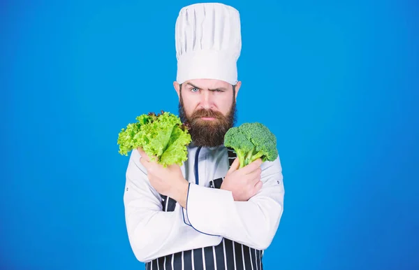 I choose vegan lifestyle. Man cook hat apron hold broccoli and lettuce. Vegan recipe concept. Buy fresh vegetables grocery store. Vegan restaurant. Hipster chief chef vegan cafe. Health and dieting