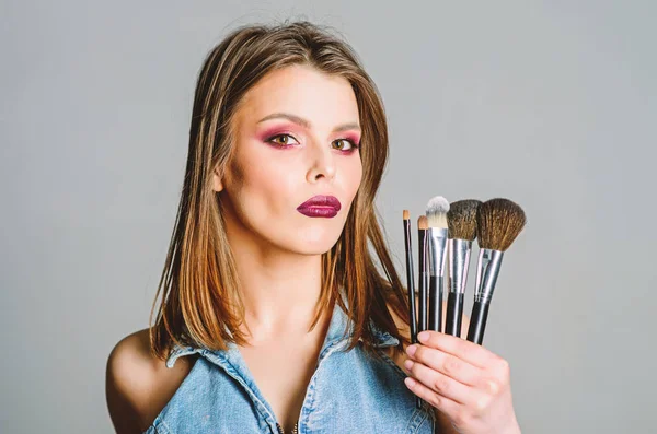 Makeup kosmetický koncept. Skin tón maskér. Obchod s kosmetikou. Dívka aplikuje oční stíny. Žena nanáší štětec na make-up. Důraz na ženskost. Profesionální make-up. Péče o pleť. Různé štětce — Stock fotografie