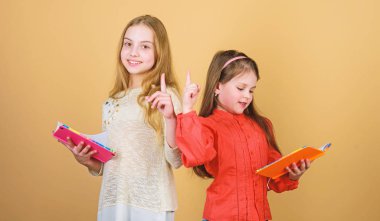 Kitaplı ya da not defteri olan çocuklar. Eğitim ve çocuk edebiyatı. En sevdiğim peri masalı. Okula geri dön. Kız kardeşler birlikte okumak için kitap seçerler. Sevimli kızlar kitapları sever. Okuryazarlık yoluyla kapıları açmak