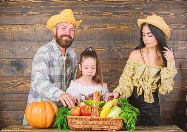 Harvest festival concept. Family farmers with harvest wooden background. Family rustic style farmers market with fall harvest. Parents and daughter celebrate harvest holiday pumpkin vegetables basket