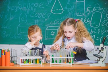 Kimya dersinde. Küçük okul çocukları derste test tüpleri tutuyorlar. Küçük kız öğrenciler okulda ders öğreniyorlar. Fen dersinde okul dersi olması