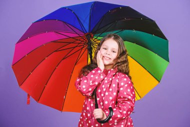 Yağmur konseptinin tadını çıkarın. Çocuk kız mutlu renkli gökkuşağı şemsiye tutun. Uygun giysiler ile yağmurlu hava. Parlak şemsiye. Birisi bulutta gökkuşağı olun. Yağmurlu bir gün eğlencesi. Şemsiye altında mutlu yürüyüş