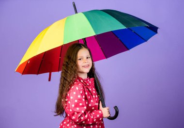 Birileri bulut gökkuşağı olun. Yağmurlu gün eğlencesi. Şemsiyenin altında mutlu bir yürüyüş. Çocuk kız mutlu renkli gökkuşağı şemsiye tutun. Uygun giysiler ile yağmurlu hava. Parlak şemsiye. Yağmur konseptinin keyfini çıkarın