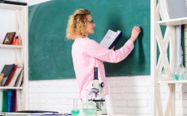 Mikrobiyoloji ve biyomühendislik. Tablo okul biyoloji öğretmeni seçici odak üzerinde kimyasal sıvılar ile mikroskop karınca tüpleri. Öğrenci yazma tebeşir tahtası defokus. Biyoloji kavramı. Biyoloji laboratuvarı