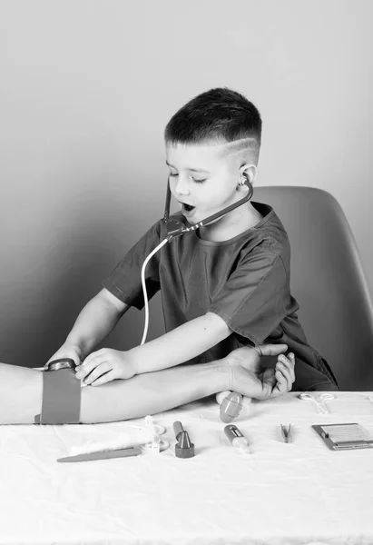 혈압 측정. 건강 검진. 의학 교육. 소년 귀여운 아이 미래 의사 경력. 의료. 아이 작은 의사는 청진기와 의료 도구와 함께 테이블을 앉아있다. 의학 개념 — 스톡 사진