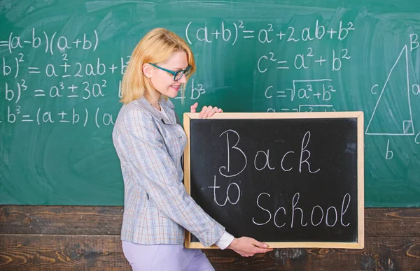 E 'di nuovo ora di scuola. Insegnante di scuola felice benvenuto agli alunni. Ottimo inizio anno scolastico. Modi migliori per accogliere gli studenti a scuola. Insegnante donna tenere iscrizione lavagna torna a scuola Immagini Stock Royalty Free