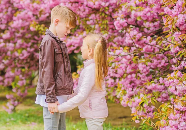 恋に落ちる春。愛のピンクの桜の子供たち。愛は空中にある。カップル愛らしい素敵な子供たちが桜の庭を歩きます。優しい愛の気持ち。小さな女の子と男の子公園でロマンチックなデート — ストック写真