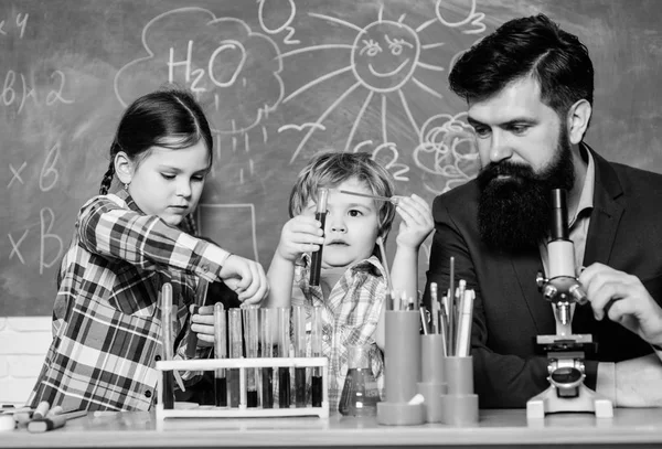 Teacher and pupils test tubes in classroom. Kids can grow in area of club such as science. Discover and explore properties of substances together. Chemistry themed club. School club education