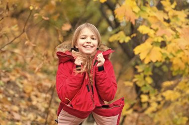 Çocuk giyim ceket sonbahar sezonu için. Giyim Sonbahar ve kavram moda. Yürüyüş çocuk sarı uzun saçlı park arka plan düşmek. Sıcak ceketle rahat hissediyorum. Kız mutlu giyim ceket kukuleta ile zevk Sonbahar Doğa
