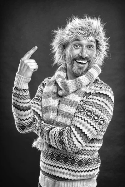 Look at this hat. A winter ensemble protects him from cold. Winter wardrobe for man. Mature fashion model enjoys cold weather style. Bearded man in sweater and scarf pointing at hat, vintage filter — Stock Photo, Image