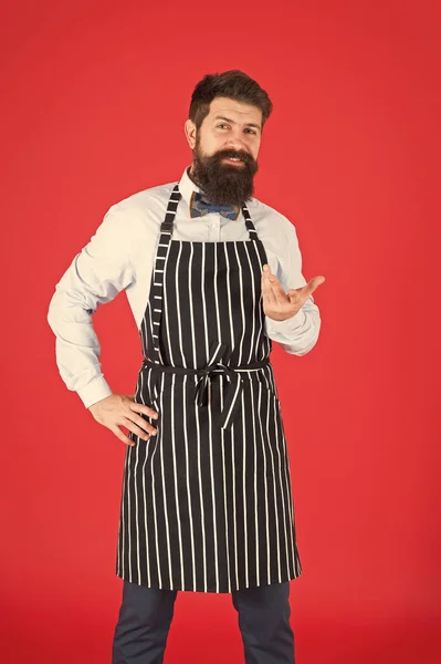 Profissional na cozinha. Homem com avental de hipster de barba. Hipster chef cozinhar fundo vermelho. Homem barbudo cozinheiro chef. Hipster cozinhar casa ou restaurante. Conceito moderno de café. Cozinhar refeições modernas — Fotografia de Stock