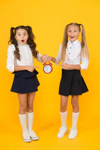 Está na hora. Horário escolar. Alunas e despertador. Alunos de escola de crianças. Dia do conhecimento. Hora da escola. Surpreendido crianças chocadas segurar despertador tempo de contagem. Latecomer será punido — Fotografia de Stock