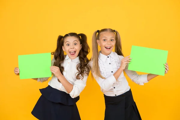 女子学校制服ホールドポスター.女子高生がポスターを見せる。ソーシャルポスターのコピースペース。社会化には、子どもたちがどのように仲良くなるかが含まれます。視覚的なコミュニケーションの概念。学校の友情 — ストック写真