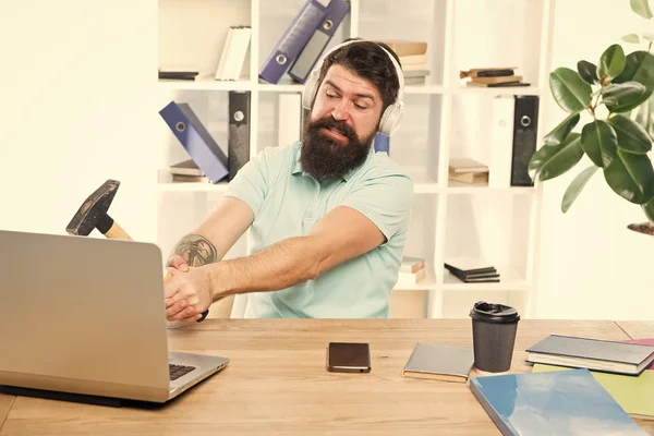 Computer lag. Reasons for computer lagging. How fix slow lagging system. Hate office routine. Man bearded guy headphones office swing hammer on computer. Slow internet connection. Outdated software