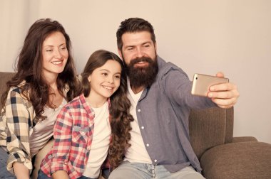 Aile birlikte hafta sonu geçirmek. Smartphone için selfie kullanın. Dostu aile birlikte eğleniyor. Anne baba ve kızı kanepede rahatlatıcı. Aile fotoğrafı için poz. Mutlu anları yakalayın. Aile selfie