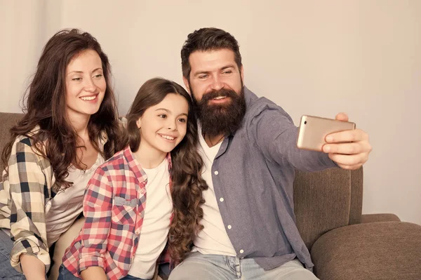 Aile birlikte hafta sonu geçirmek. Smartphone için selfie kullanın. Dostu aile birlikte eğleniyor. Anne baba ve kızı kanepede rahatlatıcı. Aile fotoğrafı için poz. Mutlu anları yakalayın. Aile selfie — Stok fotoğraf