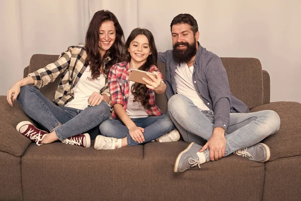 Capturar momentos felizes. A família passa o fim de semana juntos. Use smartphone para selfie. Família amigável se divertindo juntos. Mãe pai e filha relaxando no sofá. Família posando para foto. Selfie de família — Fotografia de Stock