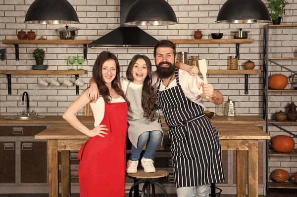 Familjedag. Mor och far med liten flicka. Lycklig familj i köket. Liten flicka med föräldrar i förkläde. Far, mor och barn kock matlagning. Familjen i köket att göra morgon frukost tillsammans — Stockfoto