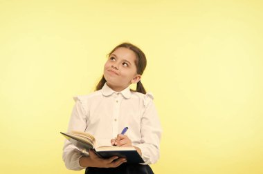 Okul üniformalı çocuk ödevlerini yapıyor. Çocuk okulu üniformaları kitap ve kalem tutuyor. Şirin kız fikir notları yaz. Hatırlanacak notlar. Kompozisyon ya da notlar yaz. Kişisel program. Not alıyorum.