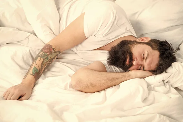 Mañana perezosa. Hombre barbudo hipster soñoliento en la cama. Por la mañana temprano. Insomnio y problemas de sueño. Relájate y duerme. El hombre barbudo duerme en sábanas blancas. Sueño saludable y bienestar — Foto de Stock