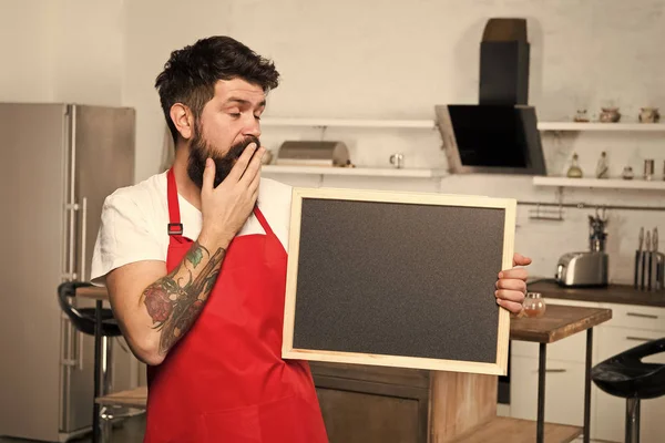 Clever ways to organize kitchen. Cook hold blank chalkboard copy space. Secret tips. Useful information. Man bearded hipster red apron stand in kitchen. Kitchen furniture store. Kitchen hacks concept