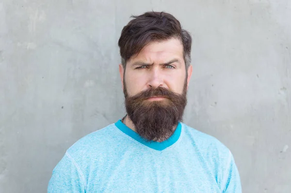 Zijn baard en kapsel zijn gestyled. Bearded Man dragen stijlvolle snor en baard vorm. Ongeschoren hipster met getextureerde baard haar op grijze muur. Serieuze blanke man met lange baard — Stockfoto