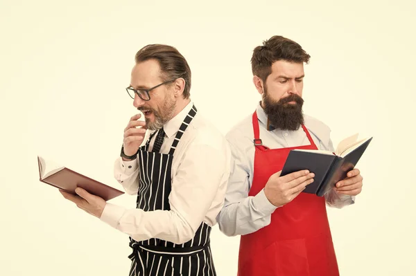 Je cherche une meilleure recette. Améliorer les compétences culinaires. Livre des recettes. Selon la recette. Hommes barbus chefs avec des livres ou des blocs-notes. Concept culinaire. Les cuisiniers amateurs lisent les recettes du livre. Essayez quelque chose de nouveau — Photo