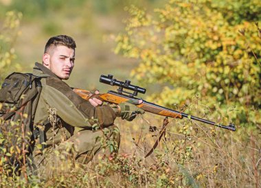 Profesyoneller için avcılık ekipmanları. Avcılık acımasız erkeksi hobi. Hunter tüfek tutun. Adam Kamuflaj giysileri doğa arka plan giymek. Av izni. Sakallı ciddi avcı eğlence avcılık harcamak