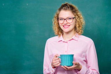 Öğretmenlik en büyük iyimserlik eylemidir. Kadın okul dersten önce kahve nin tadını çıkarır. Gözlüklü öğretmen kahve tebeşir tahtası arka plan içmek. Tüm gün boyunca enerji şarjı. Kahve bağımlısı. Kafein dozu