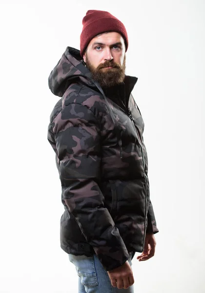 Hipster winter fashion. Comfortable winter outfit. Winter stylish menswear. Man stand warm camouflage pattern jacket parka with hood isolated on white background. Guy wear hat and black winter jacket