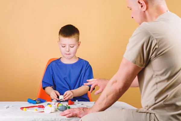 Hospital worker. Medical service. Kid little doctor sit table medical tools. Health care. Pediatrician concept. Boy cute child and his father doctor. Medical examination. Child care kindergarten