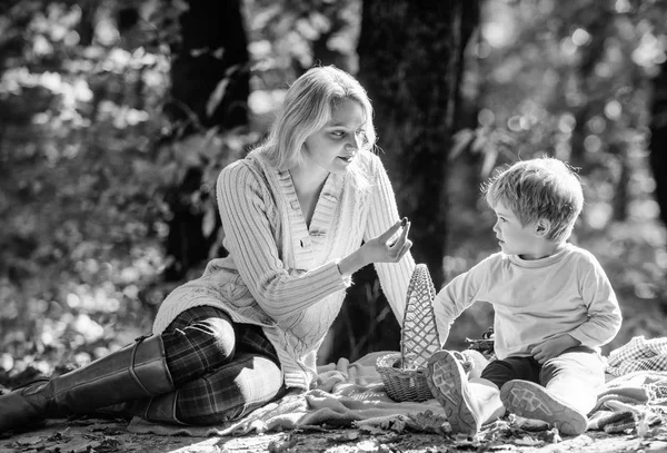 Мати гарна жінка і маленький син сидять на розслаблюючому лісовому пікніку. Добрий день для весняного пікніка в природі. Досліджуйте природу разом. Мама і хлопчик розслабляються під час походу в ліс. Сімейний пікнік — стокове фото