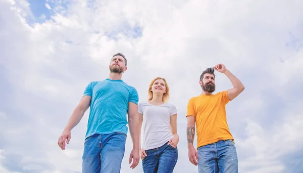 Le grand ajustement pour la journée de congé. Jeunes gens dans un style décontracté sur ciel nuageux. Groupe de personnes en tenue décontractée. Les gens de la mode ont l'air décontractés en tenue d'été. Jolie femme et les hommes amis marchant en plein air — Photo