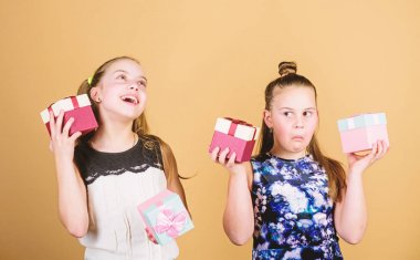 Çocuklar mutlu doğum günü hediyeleri seviyor. Alışveriş ve tatiller. Kız kardeşler hediyelerin tadını çıkarır. Çocuklar hediye kutuları bej arka plan tutun. Mutlu günler. Çocuk kızlar hediye memnun. Kızlar sevimli doğum günü kutlamak