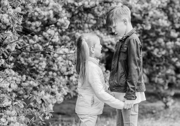 Primavera para enamorarse. Los niños enamorados flor de cerezo rosa. El amor está en el aire. Un par de adorables niños encantadores caminan por el jardín de sakura. Tiernos sentimientos de amor. Niña y niño. Cita romántica en el parque — Foto de Stock