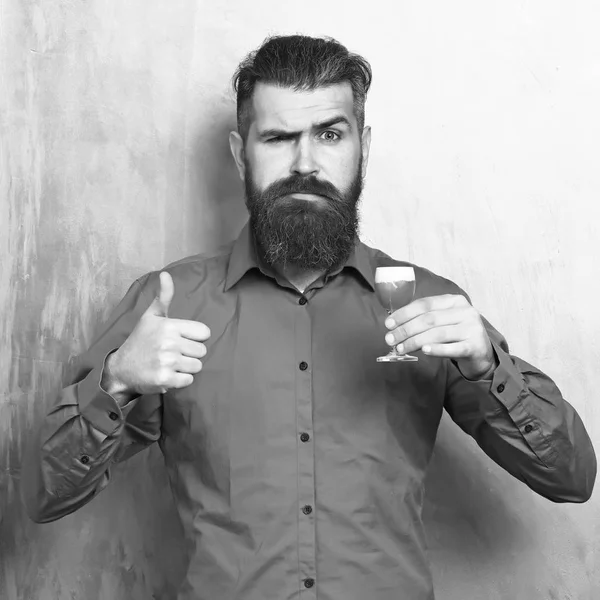 Homme barbu, longue barbe. Brutal caucasien sérieux hipster avec moustache en chemise brune tenant alcoolique coup rouge sur fond de texture dorée — Photo