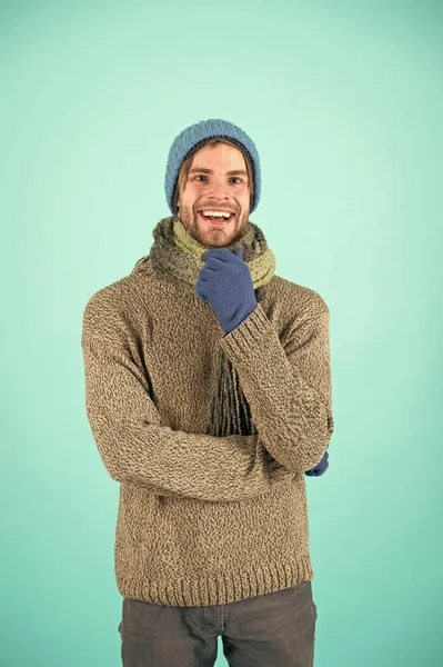 Winter fashion knitted clothes. Knitted accessories as hat and scarf. Man in knitted hat and scarf winter fashion season. Man wear knitted clothes turquoise background. Winter accessories concept