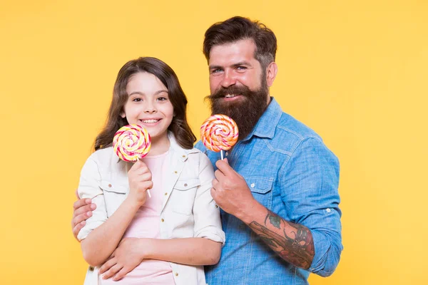 Zoete dessert. Bearded hipster goede papa voor schattige dochter. Snoep en traktaties concept. Dochter en vader eten zoete snoepjes. Lieve kindertijd. Meisje kind en papa houden kleurrijke lollies — Stockfoto