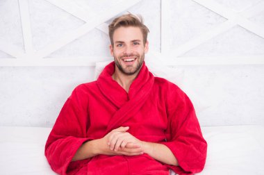 Bornozcu adam rahatlıyor. Uykuya dalmadan önce rahatlamak. Her gece yeterince uyuyun. Genel sağlık için gerekli tutarlı sirkadiyen ritim bakımı. Adam yakışıklı adam yatakta rahatlatıcı